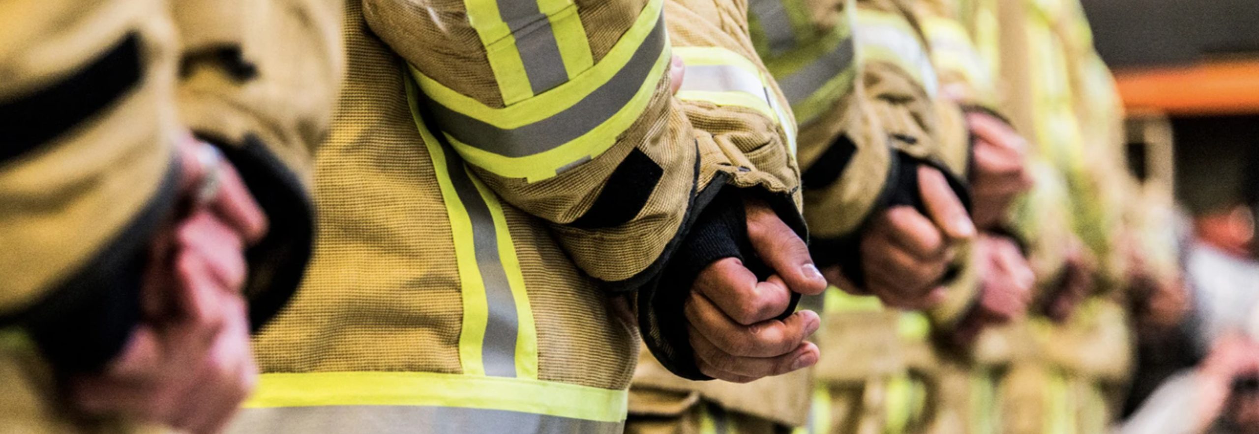 Close up photograph of firefighters with their hands crossed behind their backs.