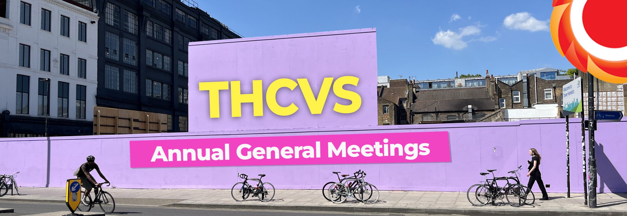 Photograph of a light purple billboard in Shoreditch. One person is cycling and one person is walking. Bikes are parked on the street. Text on the billboard: THCVS (in bright yellow) Annual General Meetings (written in white text in a pink box). THCVS logo in the top right corner.