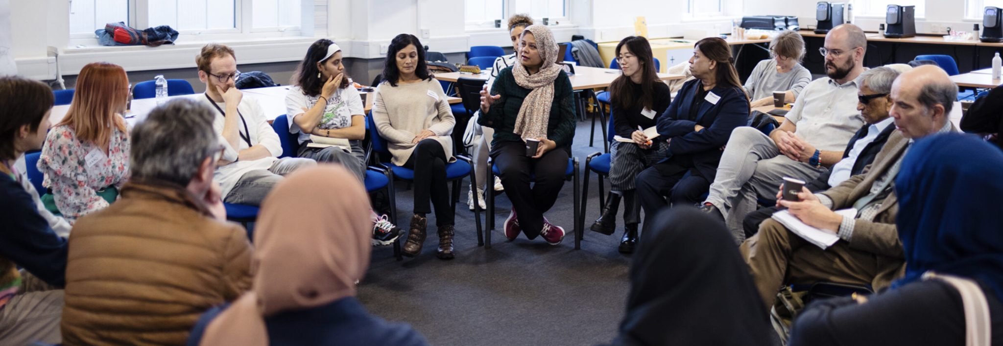 Photograph of a group of diverse people from VCS organisations sitting together in a circle having a discussion.